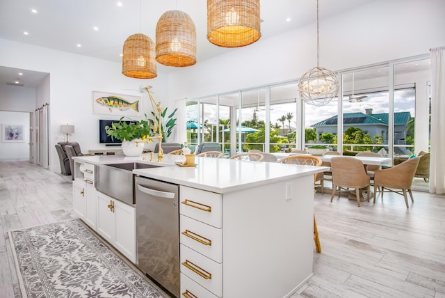 kitchen featuring a breakfast bar area, dishwasher, a kitchen island with sink, hanging light fixtures, and white cabinets