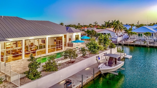 back house at dusk featuring a water view and a boat dock