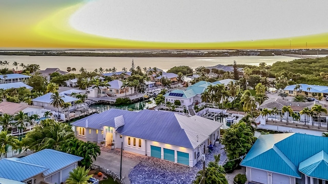 aerial view at dusk featuring a water view