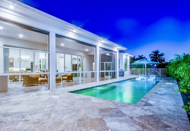 pool at dusk with pool water feature and a patio area