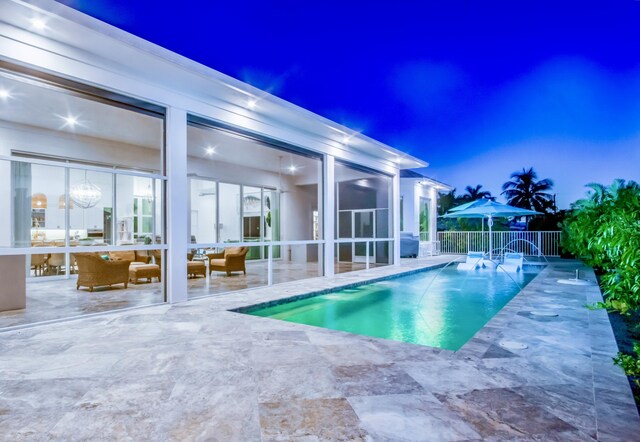 pool at dusk with a patio and pool water feature