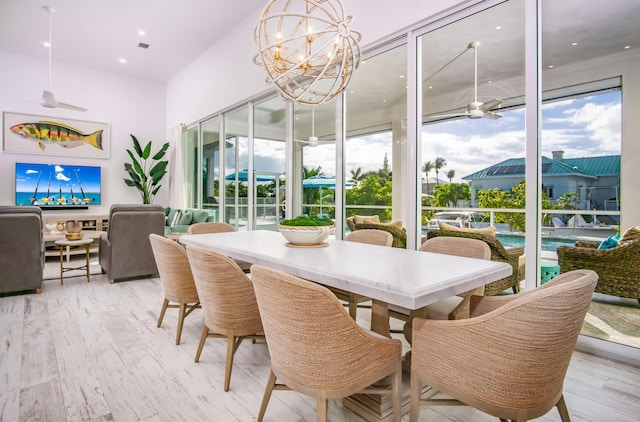 dining room featuring ceiling fan with notable chandelier and light hardwood / wood-style flooring