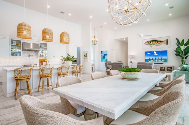 dining area with ceiling fan, light hardwood / wood-style flooring, and a high ceiling