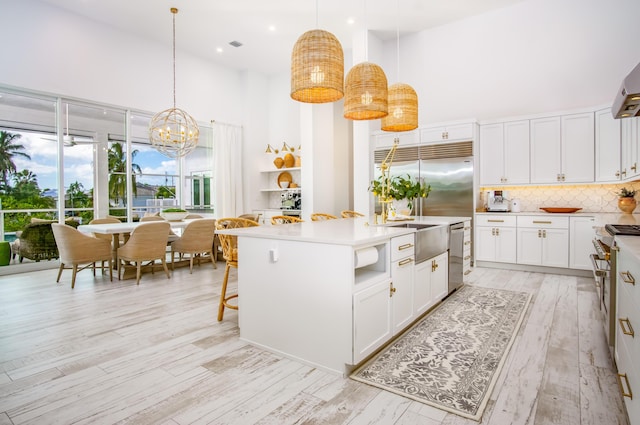 kitchen featuring a towering ceiling, a center island, hanging light fixtures, and white cabinets