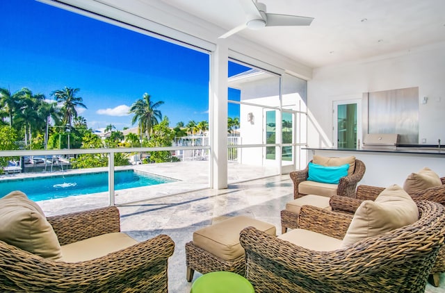 view of swimming pool featuring pool water feature, ceiling fan, an outdoor kitchen, and a patio area