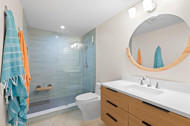 bathroom with tiled shower, vanity, toilet, and tile patterned flooring