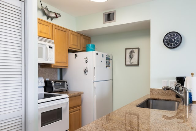 kitchen with light stone counters, sink, and white appliances