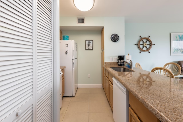 kitchen with light stone counters, white appliances, sink, and light tile patterned floors