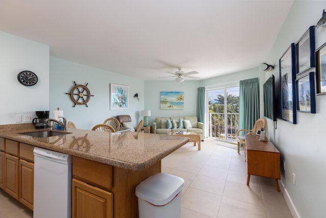 kitchen with sink, light stone counters, light tile patterned floors, dishwasher, and ceiling fan