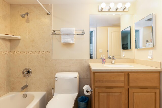 full bathroom featuring vanity, tiled shower / bath combo, tile walls, and toilet