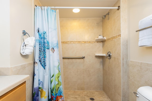 bathroom with vanity, toilet, tile walls, and walk in shower