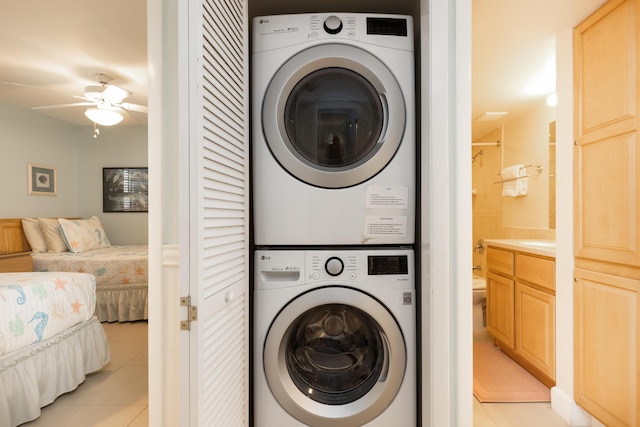 clothes washing area with light tile patterned flooring, ceiling fan, and stacked washer / dryer