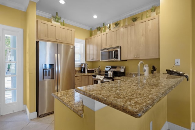 kitchen featuring light stone counters, crown molding, appliances with stainless steel finishes, light brown cabinets, and a peninsula