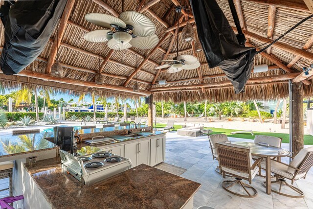 view of patio / terrace featuring a pool, a gazebo, outdoor dining space, a sink, and ceiling fan