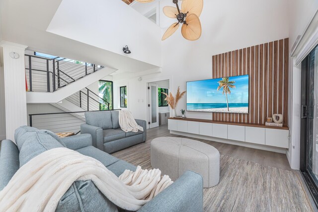 living room featuring light wood finished floors, stairway, a high ceiling, and a ceiling fan