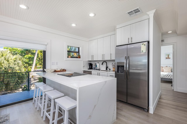 kitchen featuring a peninsula, visible vents, white cabinets, a kitchen breakfast bar, and stainless steel refrigerator with ice dispenser