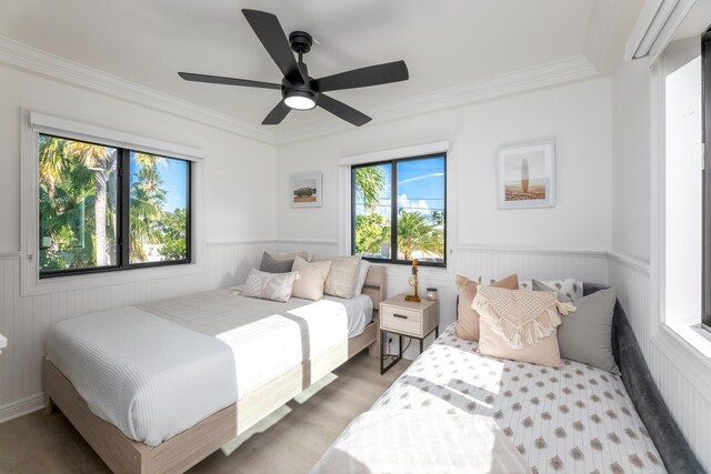 bedroom with wainscoting, crown molding, and wood finished floors