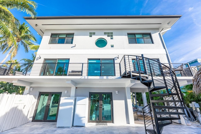 view of front facade with a patio, stucco siding, fence, a balcony, and stairs