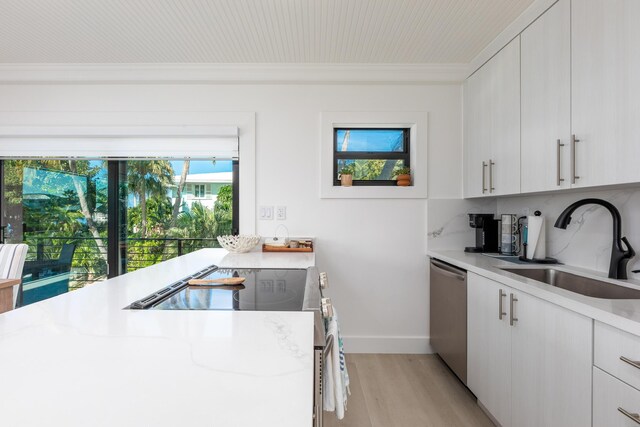 kitchen featuring white cabinets, stainless steel appliances, light countertops, light wood-type flooring, and a sink