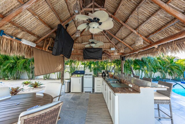 view of patio / terrace featuring a gazebo, a sink, ceiling fan, outdoor wet bar, and an outdoor pool