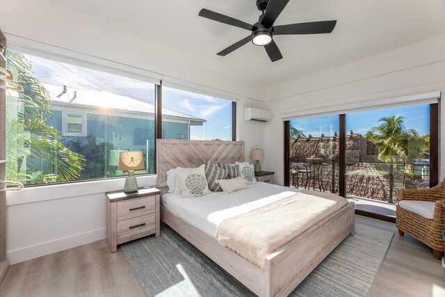 bedroom with multiple windows, wood finished floors, and a wall mounted AC