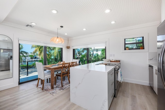 kitchen with stainless steel appliances, light wood-style floors, ornamental molding, light stone countertops, and pendant lighting