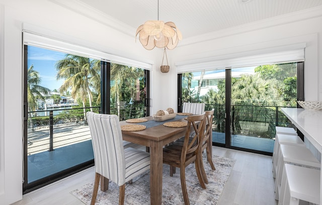 dining space with light wood-style flooring and ornamental molding