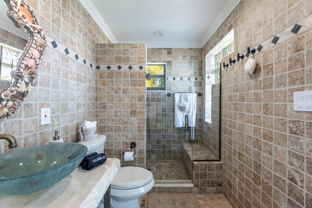 full bath featuring toilet, a sink, walk in shower, crown molding, and tile walls