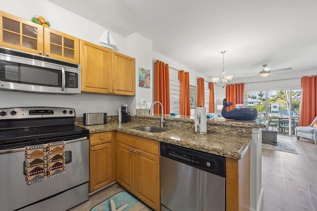 kitchen with appliances with stainless steel finishes, kitchen peninsula, sink, and dark stone counters