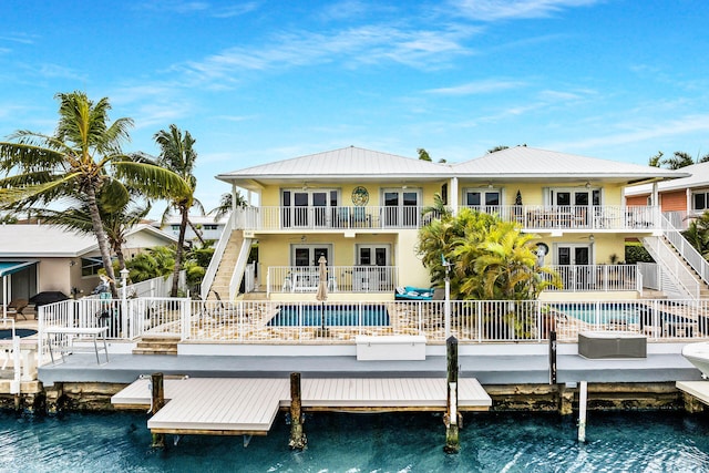 rear view of house with a water view, a balcony, and french doors