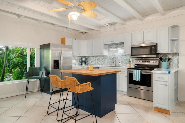 kitchen with butcher block countertops, appliances with stainless steel finishes, decorative backsplash, and a sink