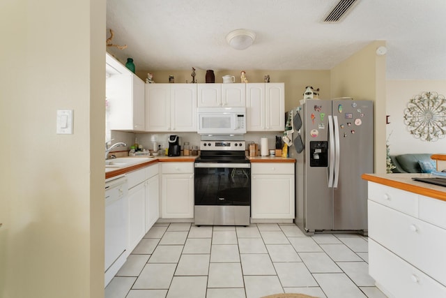 kitchen featuring light tile patterned flooring, appliances with stainless steel finishes, sink, and white cabinets