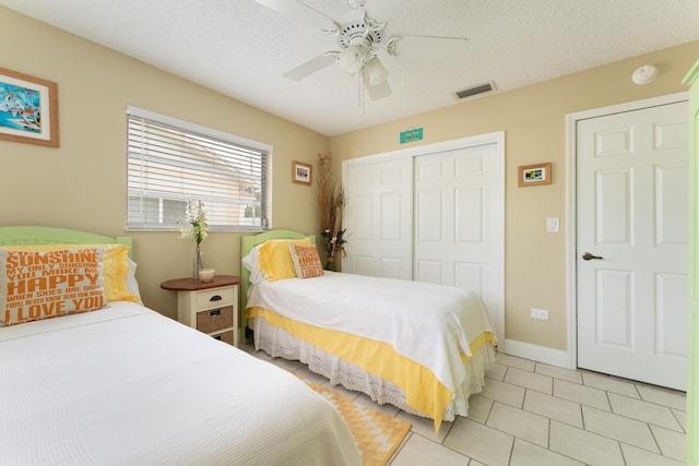 bedroom with ceiling fan, light tile patterned floors, a closet, and a textured ceiling