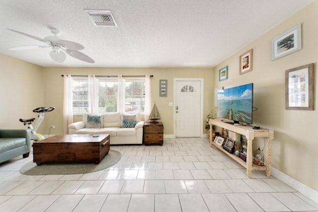 living room featuring light tile patterned flooring, ceiling fan, and a textured ceiling