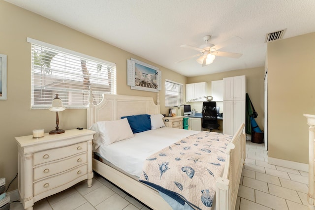 tiled bedroom with ceiling fan and a textured ceiling