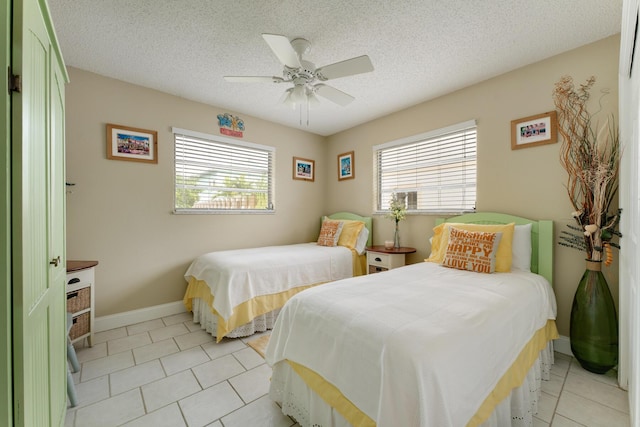 bedroom with light tile patterned flooring, ceiling fan, and a textured ceiling