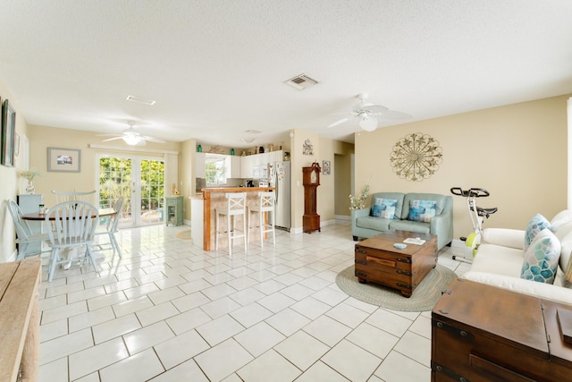 living room with light tile patterned floors, a textured ceiling, and ceiling fan