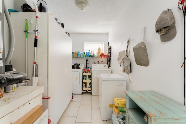 clothes washing area featuring light tile patterned floors, washer and dryer, and a textured ceiling