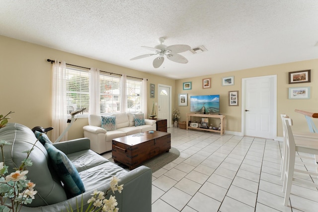 living room with ceiling fan, a textured ceiling, and light tile patterned flooring