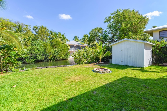 view of yard featuring a storage shed, a fire pit, and a water view