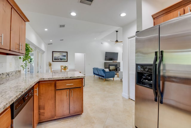 kitchen with stainless steel appliances, ceiling fan, vaulted ceiling, and light stone counters