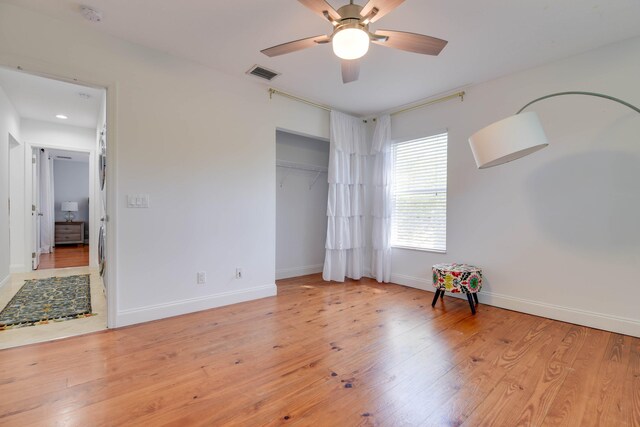 unfurnished bedroom with ceiling fan, light wood-type flooring, and a closet