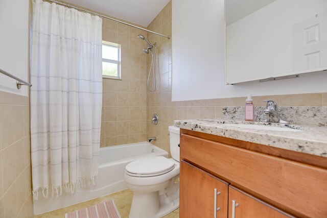 full bathroom with tile walls, vanity, shower / bath combination with curtain, tile patterned floors, and toilet