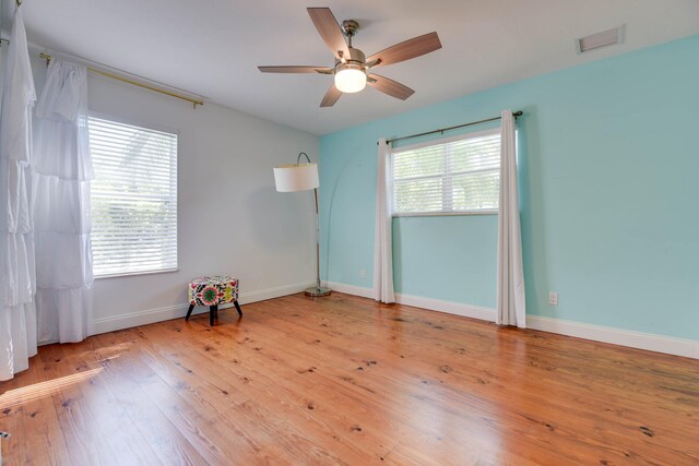 empty room featuring ceiling fan, a healthy amount of sunlight, and light wood-type flooring