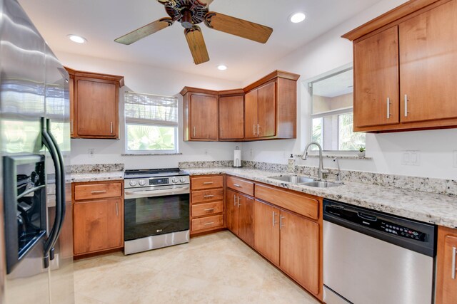 kitchen featuring sink, stainless steel appliances, ceiling fan, and light stone countertops