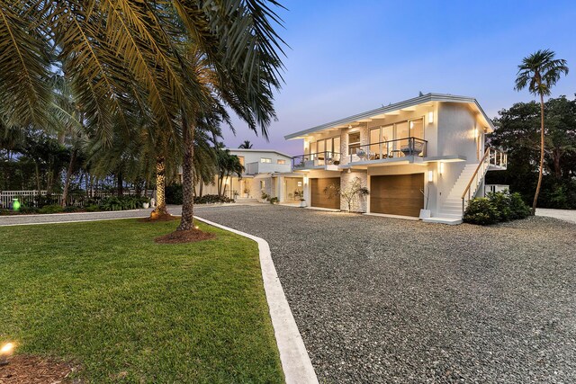 view of front of home with a garage, a lawn, and a balcony