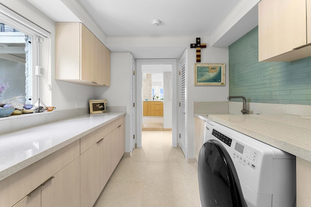 washroom with cabinets, plenty of natural light, washer / dryer, and light tile patterned floors