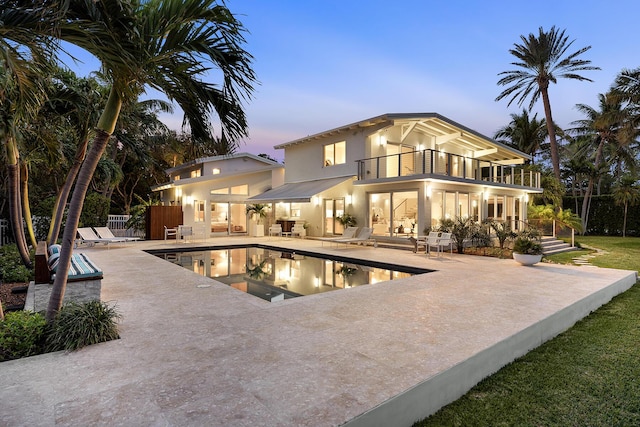 pool at dusk with a jacuzzi and a patio area