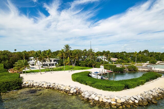 surrounding community with a water view, a yard, and a dock