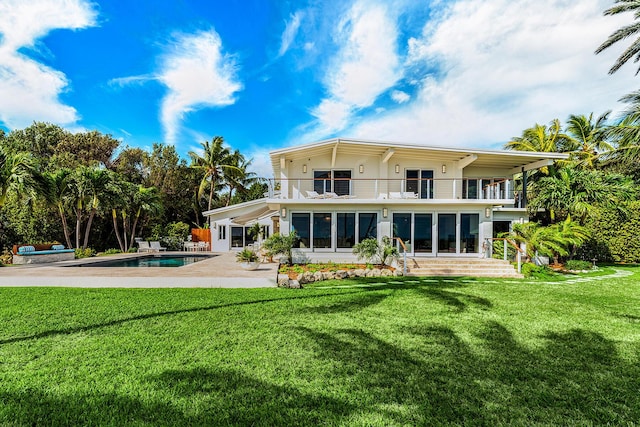 rear view of property with a balcony, a patio, and a lawn